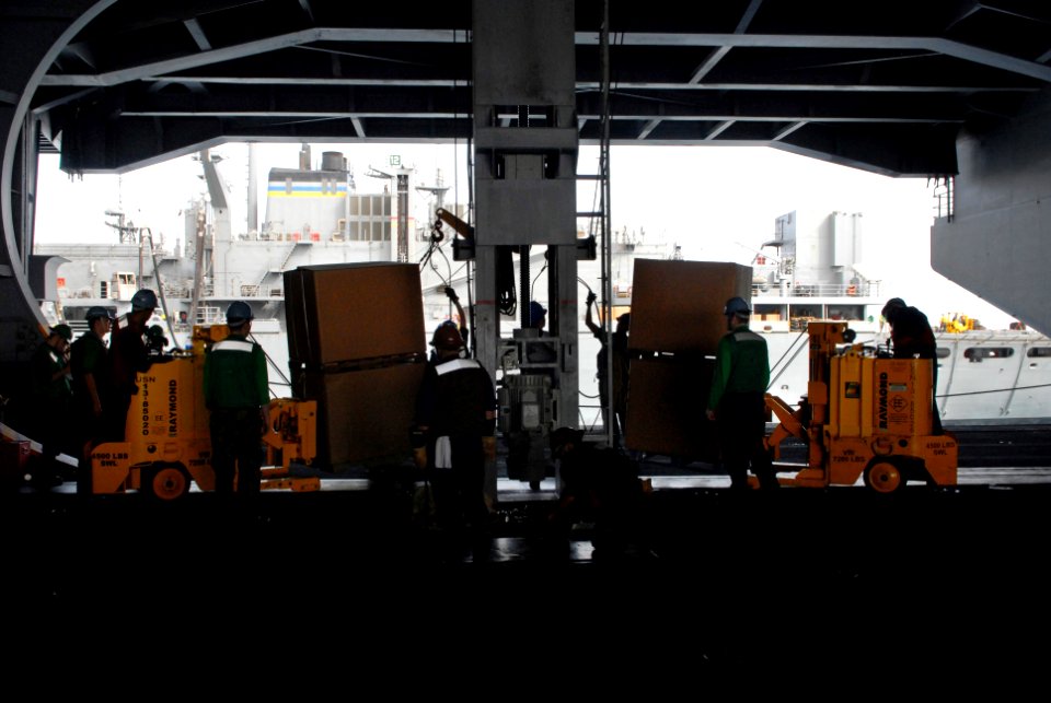 US Navy 080904-N-1635S-006 Sailors in the hangar bay of the Nimitz-class aircraft carrier USS Ronald Reagan (CVN 76) receive supplies from the Military Sealift Command fast combat support ship USNS Bridge (T-AOE 10) during a re