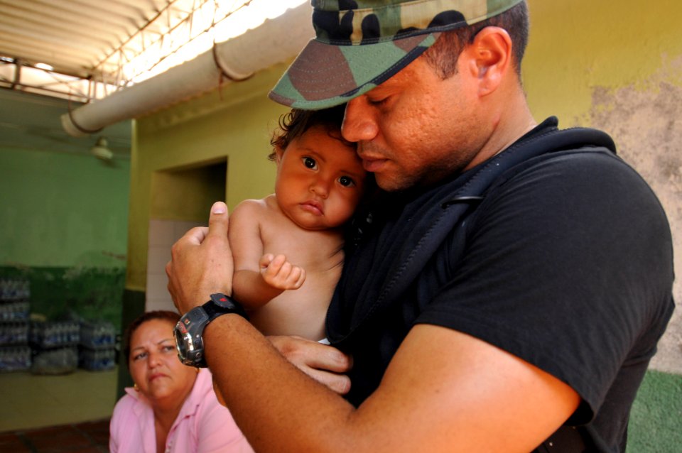 US Navy 080903-N-8907D-126 Machinist Mate 1st Class Samuel Ramos, assigned to the amphibious assault ship USS Kearsarge (LHD 3), comforts a child at the Palmira medical site during the Caribbean phase of Continuing Promise (CP)