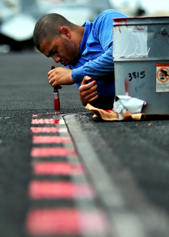 US Navy 080903-N-7981E-040 Aviation Boatswain's Mate (Handling) 3rd Class Damien Clines, from Los Angeles, Calif., repaints weapons elevator safety lines on the flight deck of the Nimitz-class aircraft carrier USS Abraham Linco