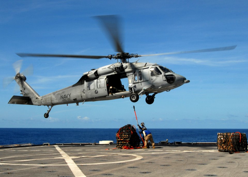US Navy 080907-N-9134V-102 Boatswain's Mate 3rd Class Willy Holland and Lance Cpl. Christopher Marchewka hook a cargo net to an MH-60S Sea Hawk helicopter