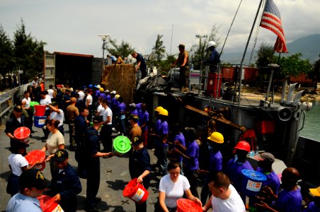 US Navy 080910-N-4515N-084 Service members embarked aboard the amphibious assault ship USS Kearsarge (LHD 3) and citizens of Port au Prince, Haiti load a landing craft utility with supplies for distribution to areas affected by