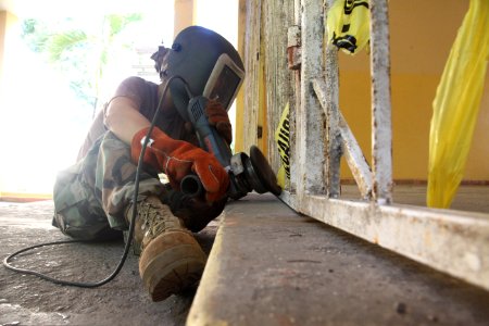 US Navy 111116-A-IP644-159 A Sailor attached to Navy Moblie Construction Battalion (NMCB) 23 strips the paint off a gate