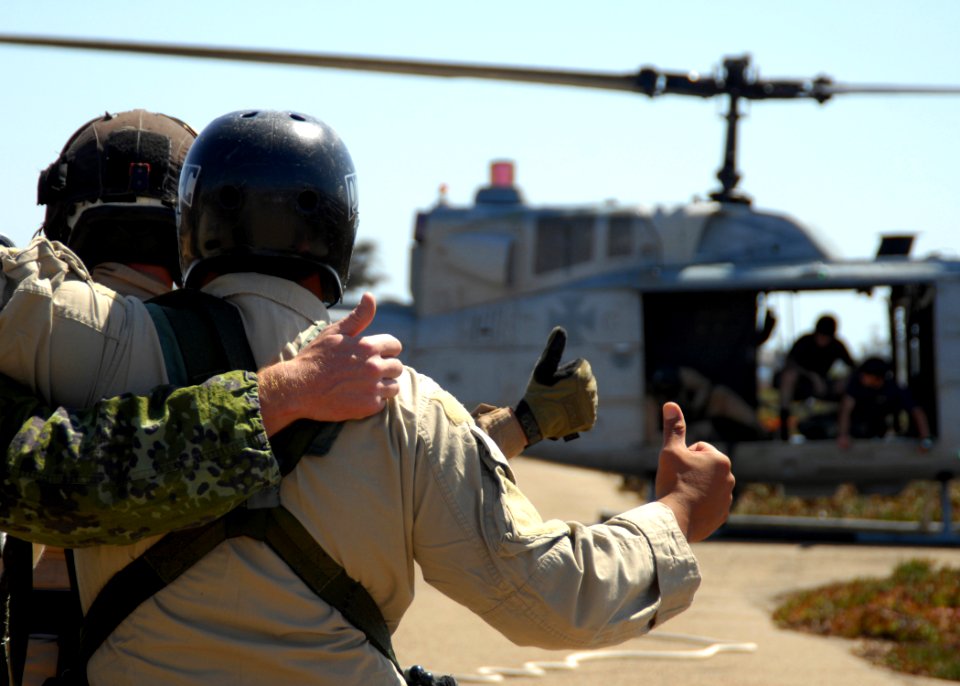 US Navy 080910-N-5366K-124 Helicopter Rope Suspension Training (HRST) students give a thumbs up to the aircrew of a UH-1 Huey helicopter before they are lifted into the air for a Special Patrol Insertion-Extraction (SPIE) exerc