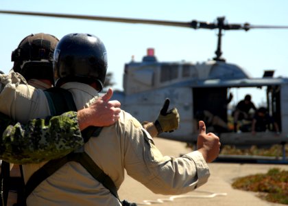 US Navy 080910-N-5366K-124 Helicopter Rope Suspension Training (HRST) students give a thumbs up to the aircrew of a UH-1 Huey helicopter before they are lifted into the air for a Special Patrol Insertion-Extraction (SPIE) exerc photo