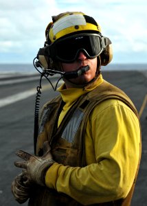 US Navy 080906-N-7981E-157 Aviation Boatswain's Mate (Handling) Airman Sean Bibby, from Dunellen, N.J., an aircraft director, communicates with flight deck control while waiting to launch an aircraft from the waist catapults on