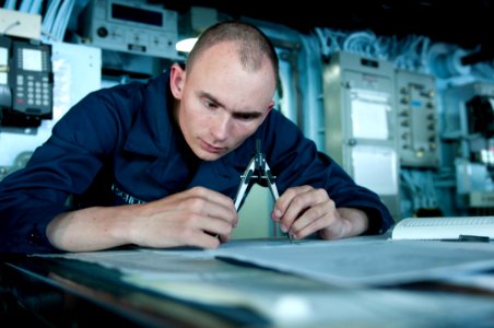 US Navy 110825-N-PM781-004 Quartermaster Seaman Michael Eschete tracks the ship's course aboard the amphibious assault ship USS Wasp (LHD 1) as the