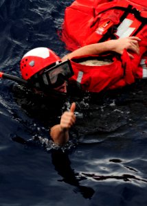 US Navy 111012-N-ED900-126 Search and rescue swimmer Fireman Walter May recovers Oscar, a man overboard rescue mannequin, and signals to be lifted