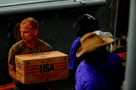 US Navy 080910-N-4515N-247 Service members embarked aboard the amphibious assault ship USS Kearsarge (LHD 3) and citizens of Port au Prince, Haiti load a landing craft utility with supplies for distribution to areas affected by photo