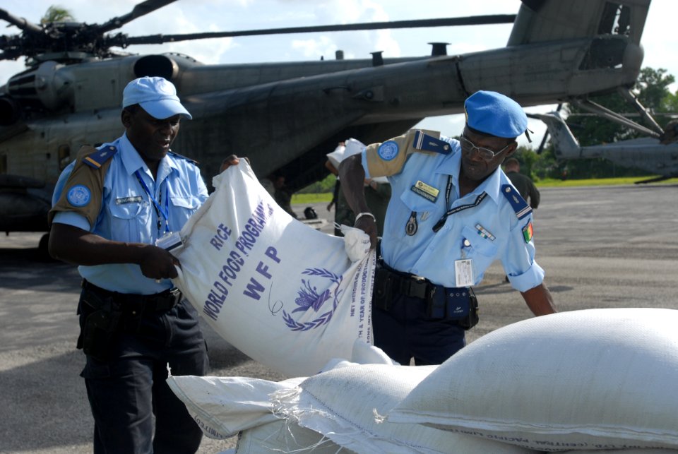 US Navy 080910-N-3595W-442 Haitian National Police work with military personnel embarked aboard the amphibious assault ship USS Kearsarge (LHD 3) to prepare food and water supplies for distribution