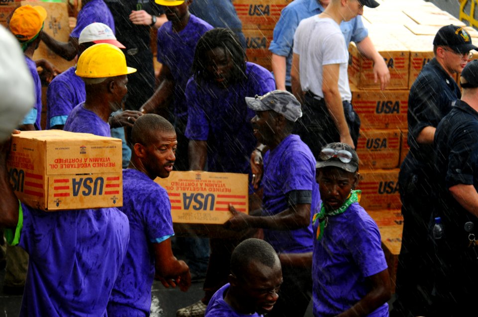 US Navy 080910-N-4515N-258 Service members embarked aboard the amphibious assault ship USS Kearsarge (LHD 3) and citizens of Port au Prince, Haiti load a landing craft utility with supplies for distribution to areas affected by
