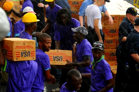 US Navy 080910-N-4515N-258 Service members embarked aboard the amphibious assault ship USS Kearsarge (LHD 3) and citizens of Port au Prince, Haiti load a landing craft utility with supplies for distribution to areas affected by