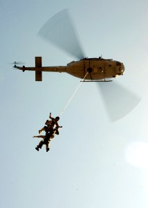 US Navy 080910-N-5366K-140 Helicopter Rope Suspension Training (HRST) students hang beneath a UH-1 Huey helicopter as they perform a Special Patrol Insertion-Extraction (SPIE) exercise during the HRST course at Naval Special Wa photo