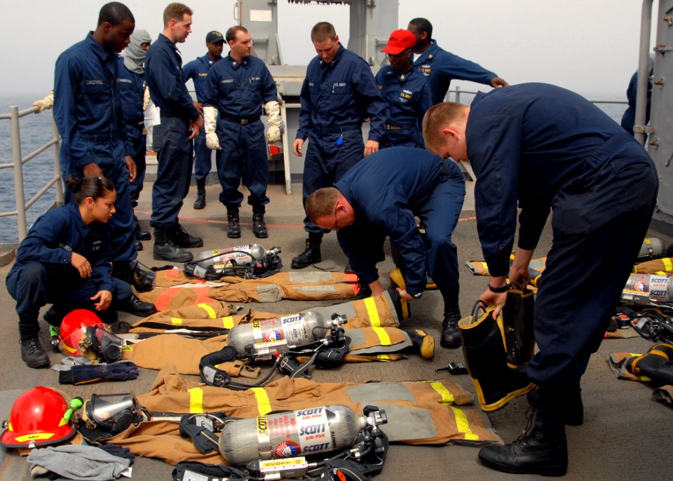 US Navy 080909-N-9134V-009 Sailors prepare to don their fire fighting ensembles during a damage control Olympics aboard the amphibious dock landing ship USS Carter Hall (LSD 50)