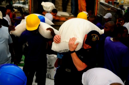 US Navy 080910-N-4515N-473 Service members embarked aboard the amphibious assault ship USS Kearsarge (LHD 3) and citizens of Port au Prince, Haiti load a landing craft utility with supplies for distribution to areas affected by photo