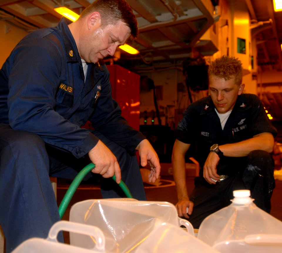 US Navy 080912-N-7544A-024 Chief Gunner's Mate William Walker and Aviation Ordnanceman 3rd Class Chris West, both embarked aboard the amphibious assault ship USS Kearsarge (LHD3) fill two-and-a-half gallon water containers