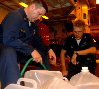 US Navy 080912-N-7544A-024 Chief Gunner's Mate William Walker and Aviation Ordnanceman 3rd Class Chris West, both embarked aboard the amphibious assault ship USS Kearsarge (LHD3) fill two-and-a-half gallon water containers