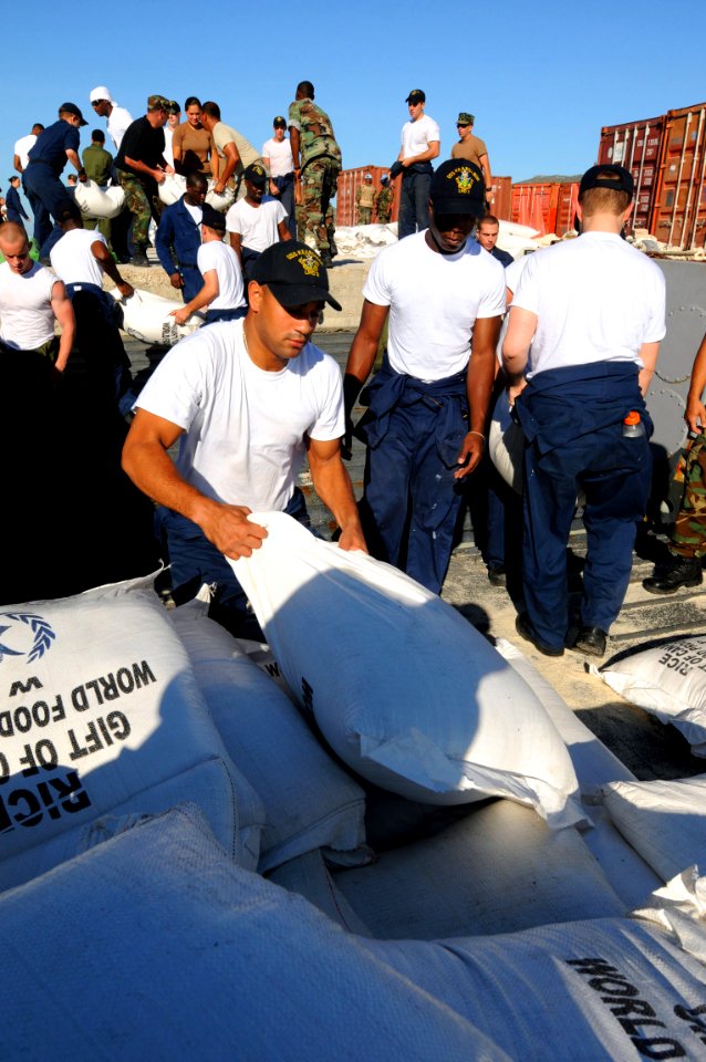 US Navy 080915-N-7955L-006 Aviation Boatswains Mate (Handling) Airman Franklin Lopez, embarked aboard the amphibious assault ship USS Kearsarge (LHD 3), moves bags of rice from a landing craft during a humanitarian assistance m