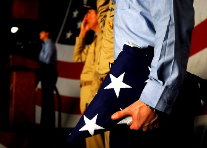 US Navy 080911-N-2183K-006 MC2 Scott A. Webb holds a flag as Seaman Heyliana Primera sings the Star Spangled Banner during a memorial ceremony aboard USS Peleliu (LHA 5) to honor those lost during the Sept. 11, 2001 terrorists