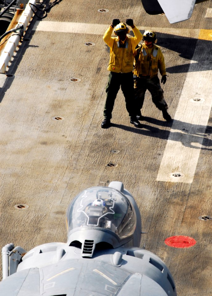 US Navy 080912-N-2183K-054 A landing signalman enlisted uses hand signals to direct an AV-8B Harrier on the flight deck of the amphibious assault ship USS Peleliu (LHA 5) during flight operations