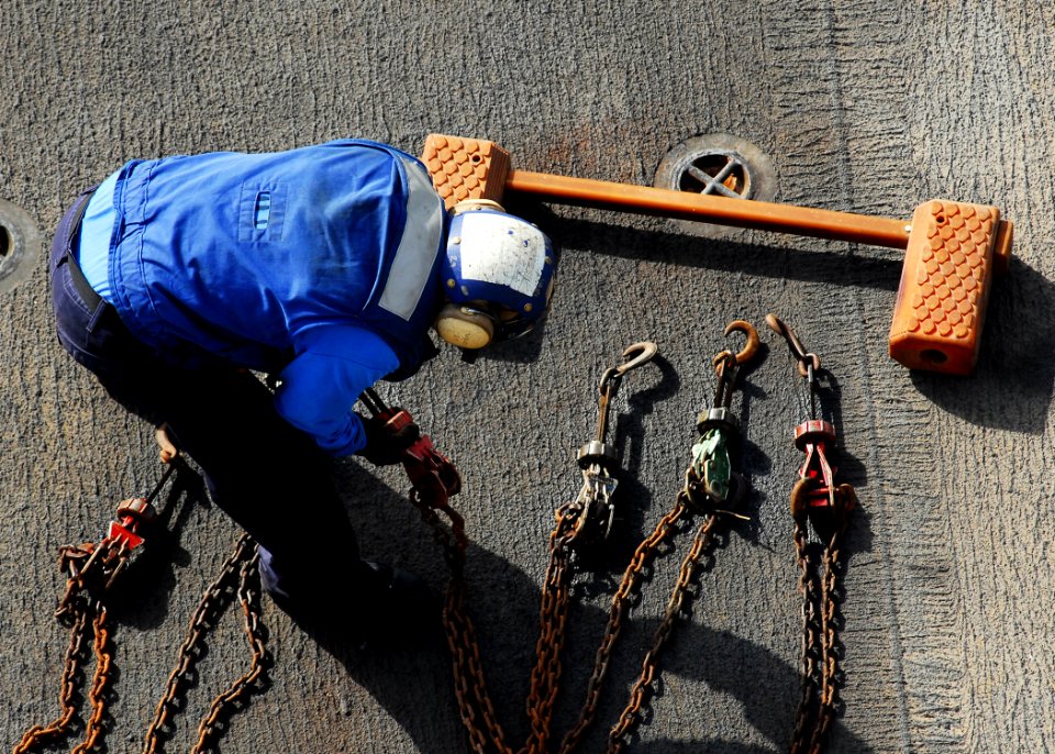 US Navy 080912-N-2183K-001 A flight deck crewman prepares the chains to secure aircraft to the flight deck of the amphibious assault ship USS Peleliu (LHA 5) during flight operations
