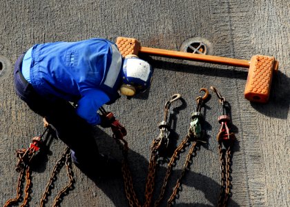 US Navy 080912-N-2183K-001 A flight deck crewman prepares the chains to secure aircraft to the flight deck of the amphibious assault ship USS Peleliu (LHA 5) during flight operations