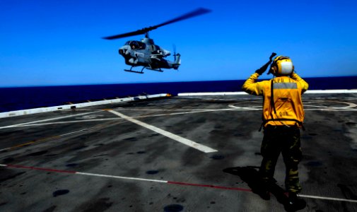 US Navy 110623-N-OS574-106 Aviation Boatswain's Mate (Handling) 3rd Class Edward Toby directs an AH-1W Cobra attack helicopter as it powers down