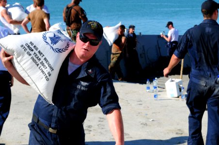 US Navy 080915-N-7955L-072 Aviation Boatswains Mate (Handling) 3rd Class Jordan Garret carries rice from a landing craft during a humanitarian assistance mission in Haiti photo