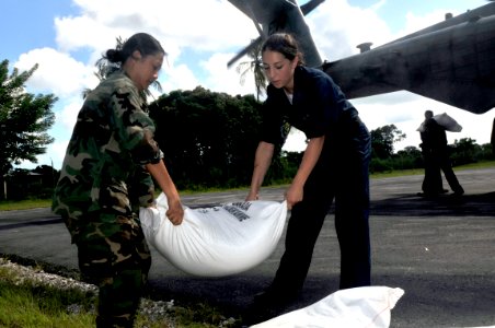US Navy 080912-N-5642P-101 Hospital Corpsman 3rd Class Reyln Pandophino and Seaman Courtney Cresta, both assigned to the amphibious assault ship USS Kearsarge (LHD 3), help unload rice bags from a CH-53 Super Stallion