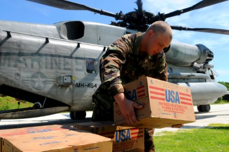 US Navy 080913-N-7955L-077 Equipment Operator Constructionman Jeffery Reaves, embarked aboard the amphibious assault ship USS Kearsarge (LHD 3), moves boxes of disaster relief supplies photo