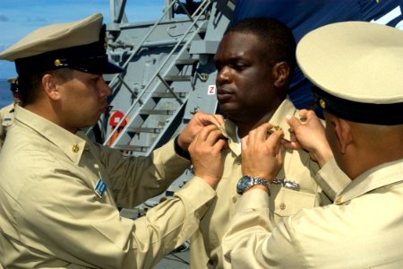 US Navy 080916-N-9123L-002 Chief Storekeeper Joel Fababier and Chief Culinary Specialist Ramon Angeles pin anchors on Chief Culinary Specialist Travin Harrell