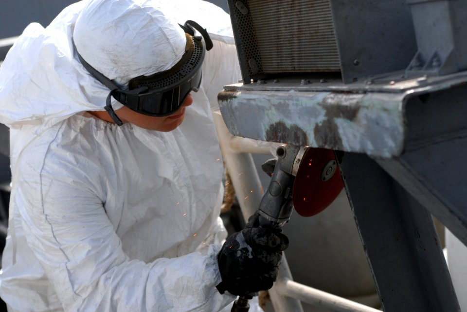 US Navy 080919-N-1635S-003 Aviation Boatswain's Mate (Handling) Scott Busby uses a power-sander to service the catwalk on the flight deck of the Nimitz-class aircraft carrier USS Ronald Reagan (CVN 76)