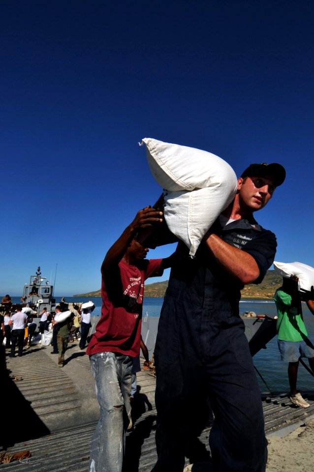 US Navy 080915-N-8907D-284 Gunner's Mate 2nd Class Shaun Reagan, embarked aboard the amphibious assault ship USS Kearsarge (LHD 3), carries a sack of rice during a humanitarian assistance mission in Haiti