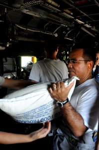 US Navy 080917-N-5642P-104 t. Cmdr. Thomas Carmos helps load a CH-53 Super Stallion with disaster relief supplies