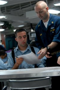 US Navy 080919-N-7730P-082 Seaman Spencer Oxley is given his advancement exam back by Chief Boatswain's Mate John Rolon after returning from a restroom break