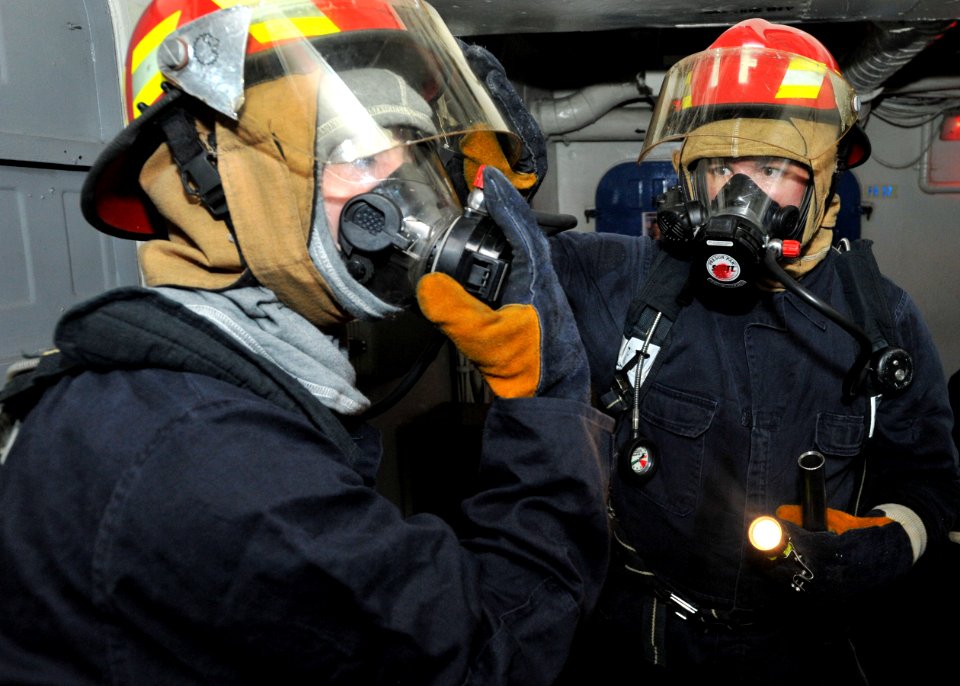US Navy 110510-N-0569K-011 Fire party investigators go on air to breathe through their masks before entering a space to investigate damage during a