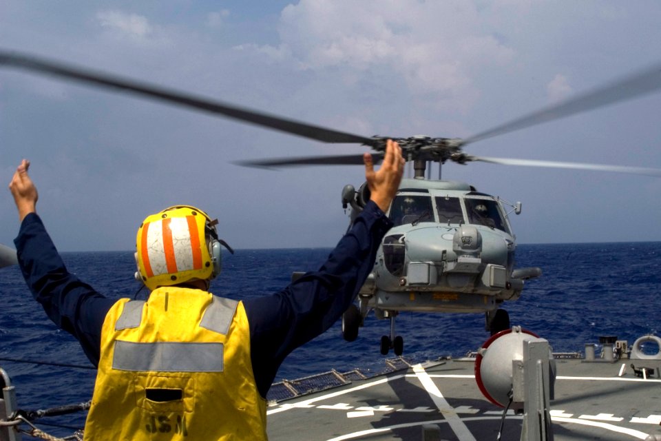 US Navy 080918-N-9123L-004 Boatswain's Mate Seaman Brett Kish, from Cleveland, guides an SH-60 Sea Hawk helicopter during flight quarters aboard the guided-missile destroyer USS John S. McCain (DDG 56)