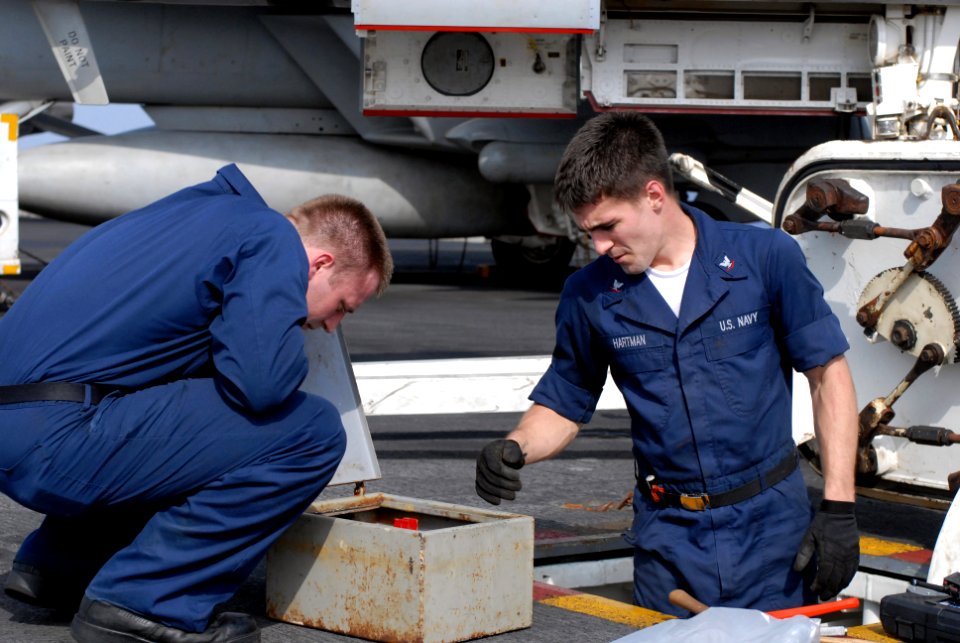 US Navy 080919-N-1635S-001 Electronics Technician 2nd Class Robert Brimberry, left, and Electronics Technician 3rd Class Daniel Hartman perform maintenance on an alignment outlet box