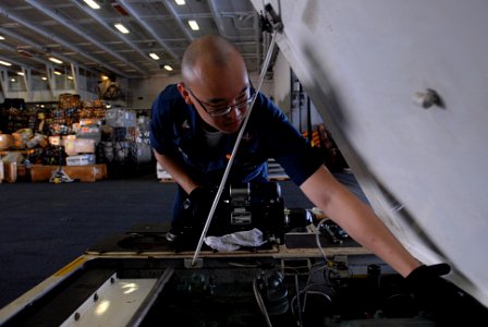 US Navy 080917-N-3610L-224 Aviation Support Equipment Technician 3rd Charles Yeh reaches into a tractor to replace a damaged spark plug