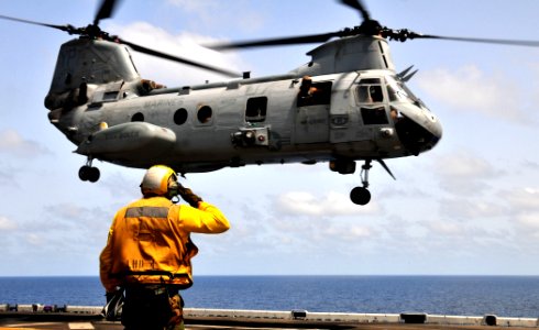 US Navy 110506-N-ZS026-256 Aviation Boatswain's Mate (Handling) 3rd Class Paco Dammons salutes pilots aboard a CH-46 Sea Knight helicopter