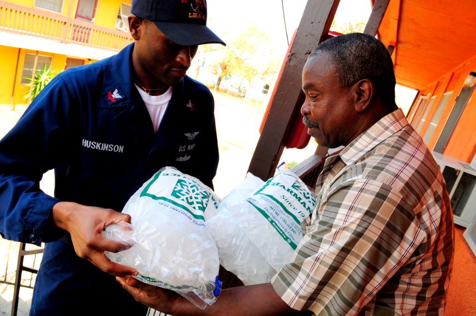 US Navy 080921-N-5758H-238 Air Traffic Controller 2nd Class Earle Huskinson, assigned to the amphibious assault ship USS Nassau (LHA 4), gives a bag of ice to Galveston resident Lloyd Smith