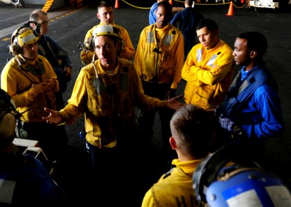 US Navy 080921-N-7241L-003 Aviation Boatswain's Mate 2nd Class Kevin Nabors, center, speaks to shipmates in the hangar bay of the Nimitz-class aircraft carrier USS Theodore Roosevelt (CVN 71)