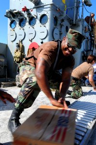 US Navy 080922-N-7955L-055 Hospital Corpsman 3rd Class Mikel Frazier, an individual augmentee assigned to the amphibious assault ship USS Kearsarge (LHD 3), moves a box of cooking oil