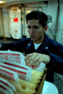 US Navy 080919-N-7730P-071 Personnel Specialist 3rd Class Gregorio Villalba sorts through and alphabetizes the E-4 exam answer sheets as Sailors turn in their finished exams aboard the Nimitz-class aircraft carrier USS Ronald R