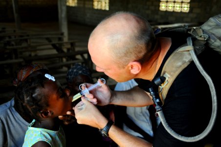 US Navy 080920-N-4515N-273 Maj. Darin Gunnink, a medical augmentee embarked aboard the amphibious assault ship USS Kearsarge (LHD 3), gives a child de-worming medication during disaster relief efforts in Haiti photo