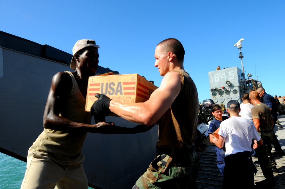 US Navy 080922-N-7955L-073 Hospital Corpsman 3rd Class Mikel Frazier, an individual augmentee assigned to the amphibious assault ship USS Kearsarge (LHD 3), moves boxes of cooking oil