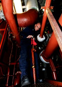 US Navy 110513-N-DU438-076 Electrician's Mate Fireman Barrett P. Smith lowers a sounding tube into a main reduction gear sump inside an engine room