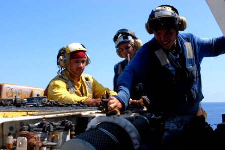 US Navy 080920-N-9950J-017 Aviation Boatswain's Mate (Handling) 2nd Class Isaac Berwick, left, Aviation Boatswain's Mate (Handling) Airman Victor Curiel and Aviation Boatswain's Mate (Handling) Airman Sheldon Victorine work on