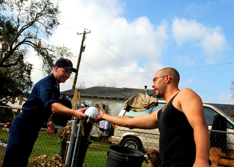 US Navy 080921-N-5758H-141 Engineman 1st Class Robert Chapman, assigned to the amphibious assault ship USS Nassau (LHA 4), hands out breathing masks to a Galveston resident