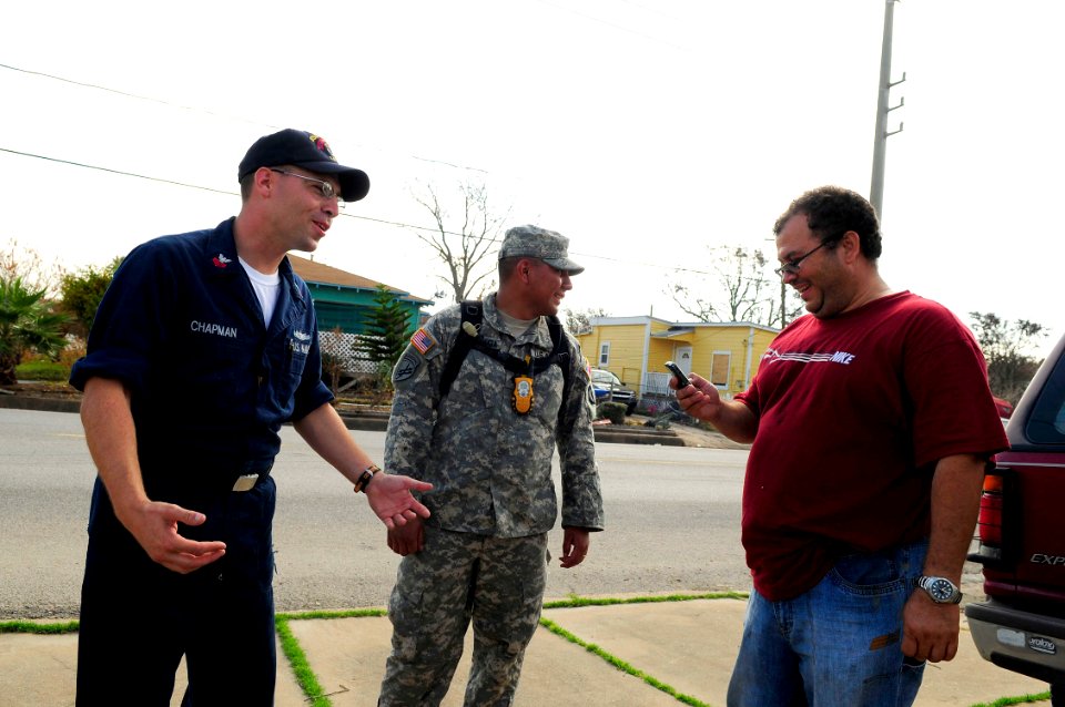 US Navy 080921-N-5758H-122 Engineman 1st Class Robert Chapman, left, assigned to the amphibious assault ship USS Nassau (LHA 4), and Sgt. Jainesan Garza of the Army National Guard, share a joke with a Galveston resident