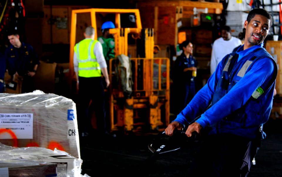 US Navy 110414-N-7488A-066 Aviation Boatswain's Mate (Handling) Airman Apprentice Louis Coleman transports cargo across the hangar bay aboard the